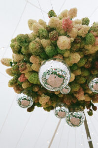 Close-up of wedding floral ball with green cream and blush hydrangeas and hanging silver disco balls