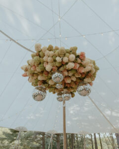 Large spherical wedding floral installation with cream yellow blush hydrangeas and silver disco balls hanging in tent